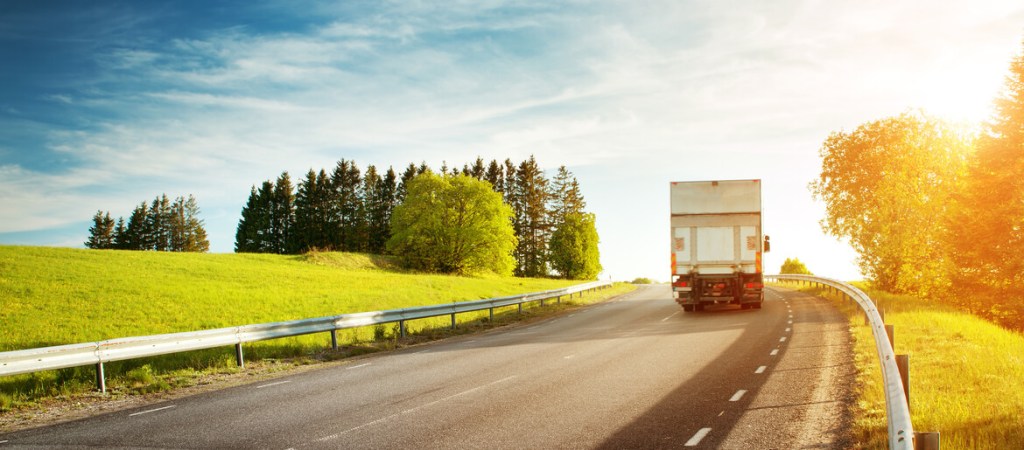 Back of truck driving past sunny field