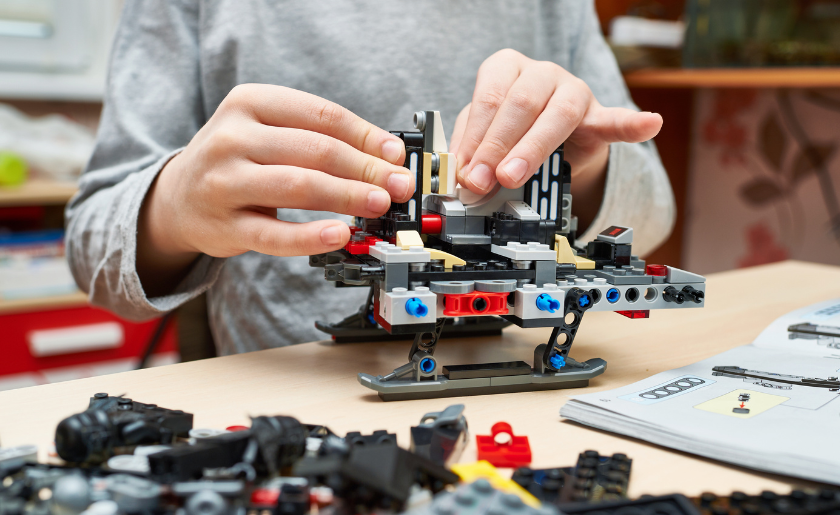 Building LEGO set on table with use instructions