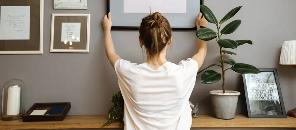 Woman putting a picture up on a wall