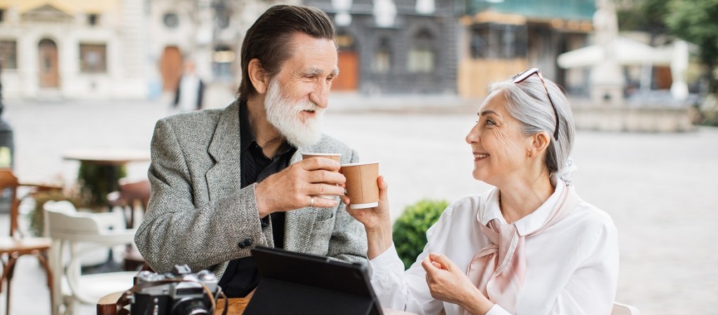 Stylish senior couple on cafe terrace drinking coffee