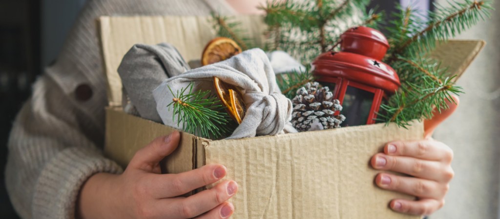 person carrying a cardboard box filled with christmas decorations