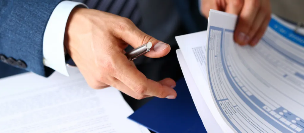 businessman in blue suit holding documents and a pen