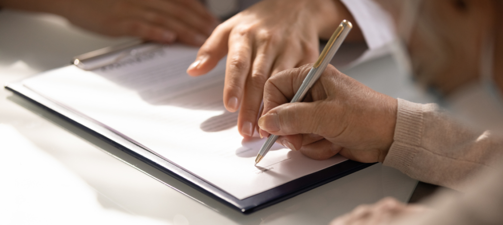 person signing a document using a pen