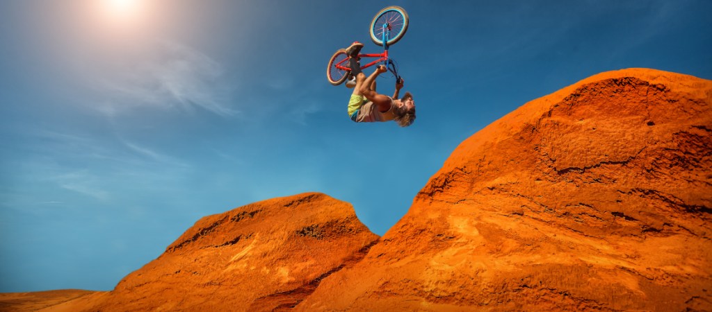 upside down mountain bicyclist in midair over orange desert rocks