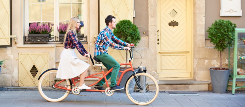 couple in casual clothing, bearded man and blond woman in glasses cycling