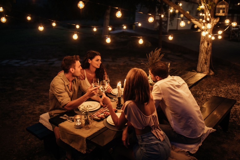 Cropped shot of four handsome friends having dinner in the backyard