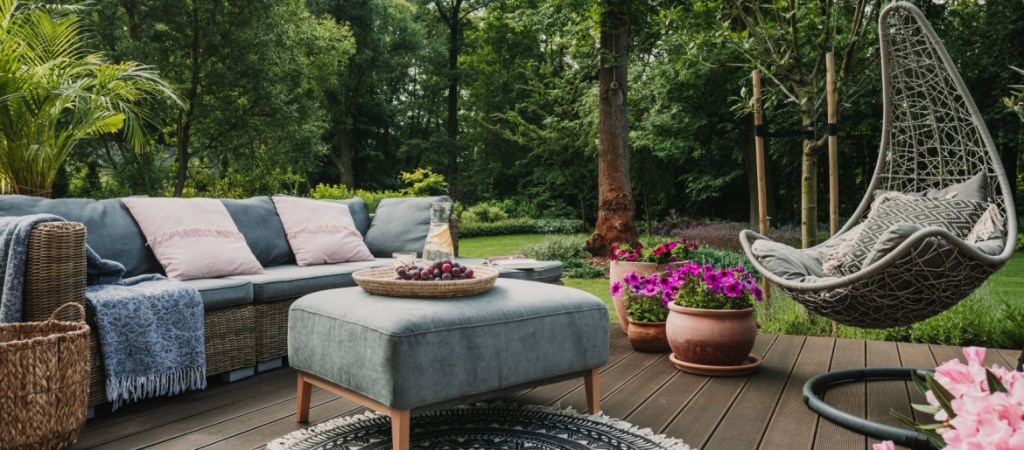 Garden patio decorated with Scandinavian wicker sofa and coffee table