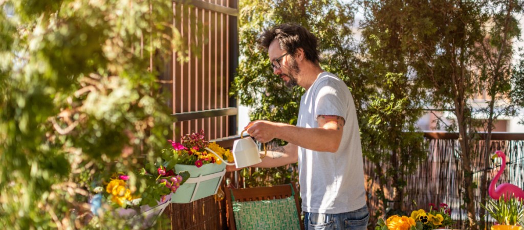 Young man taking care of his plants on the balcony