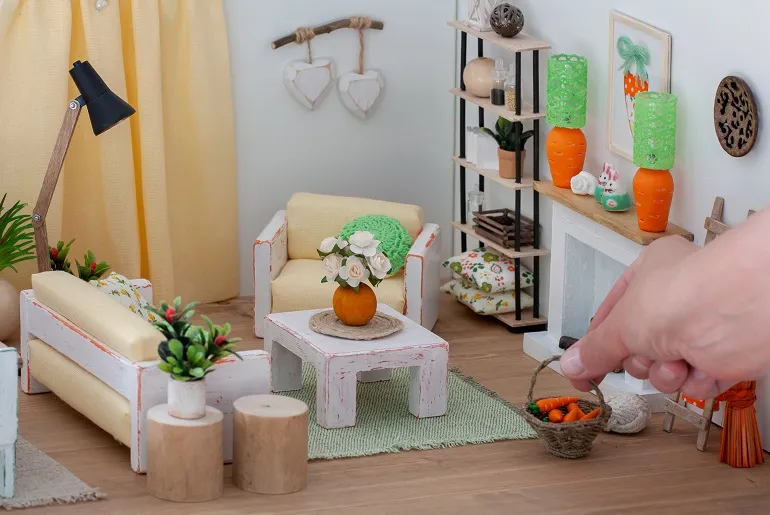 A Woman Adding Furniture to a Dollhouse