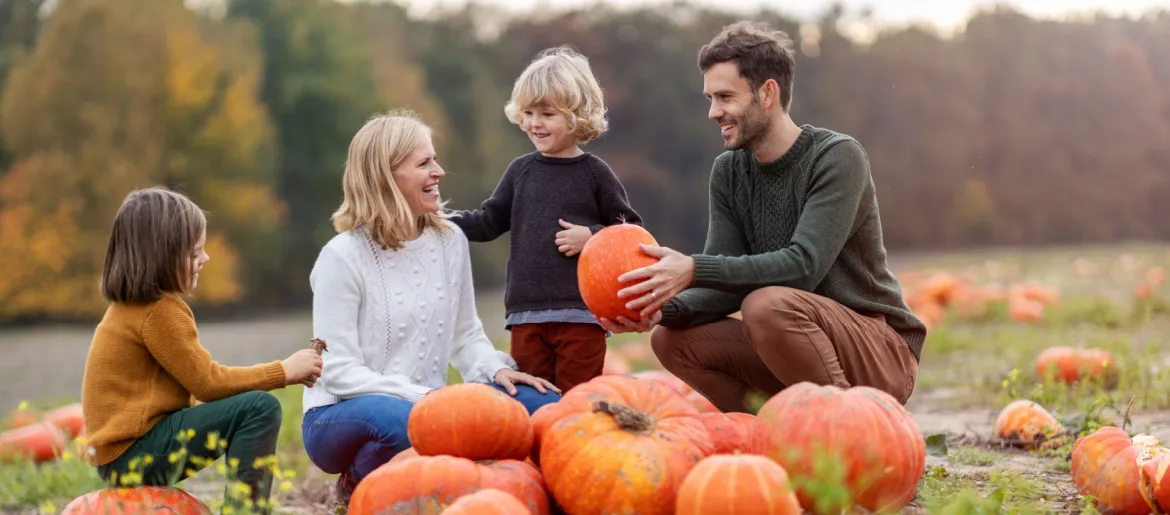 Happy young family in pumpkin patch field