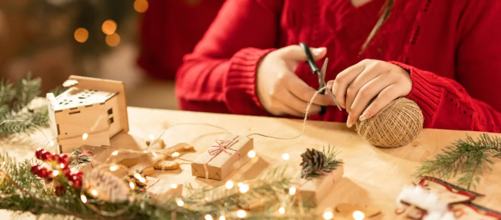 a girl with her own hands makes a Christmas decor for the house. Merry Christmas and happy new year concept. Girl packing Christmas gift box.