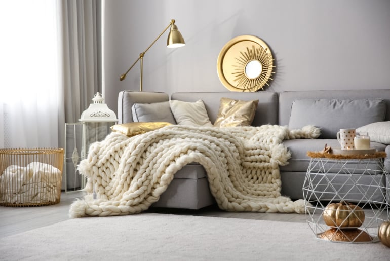 Cozy living room interior with knitted blanket on comfortable sofa
