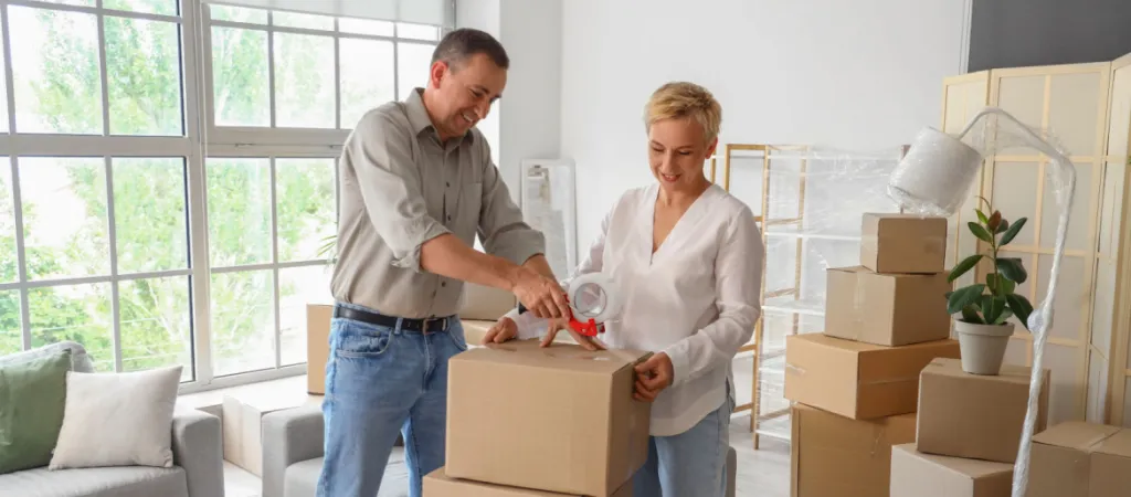 Gen X US Migration Destination Mature couple taping box in room on moving day