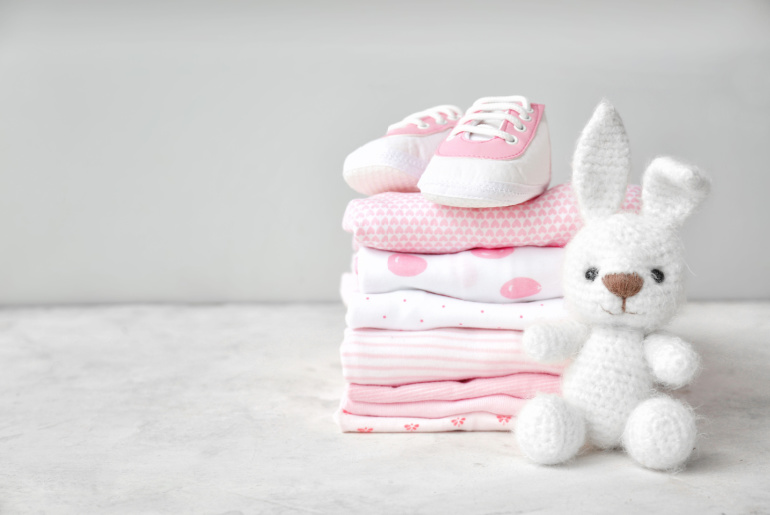 Stack of clothes, shoes and toy on table