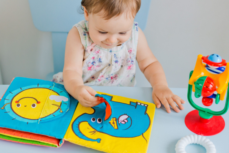 small child playing with soft book