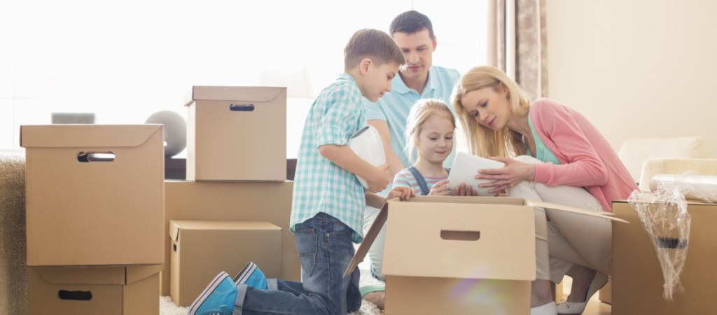 Family unpacking cardboard boxes at new home
