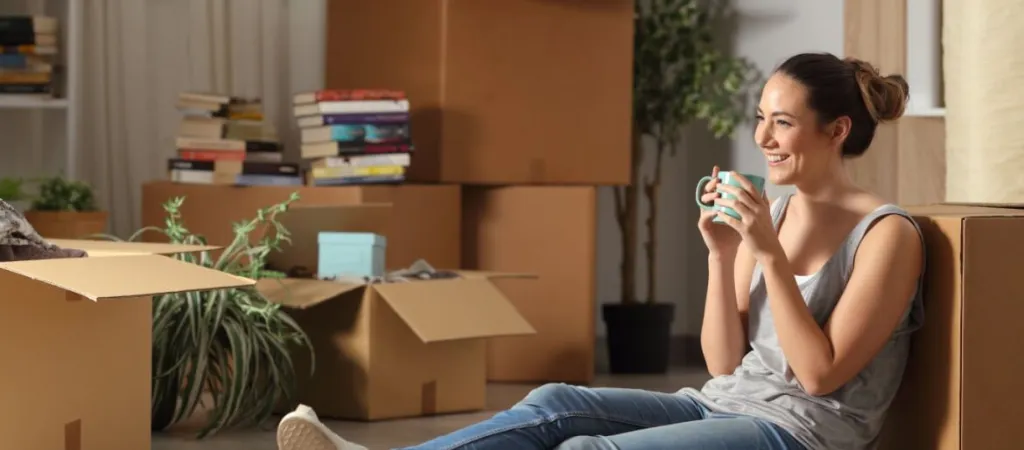 Young person surrounded by moving boxes in new home