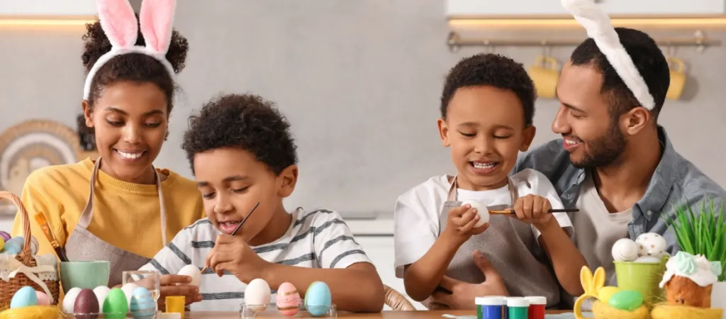 Happy African American family with Easter eggs at table in kitchen.