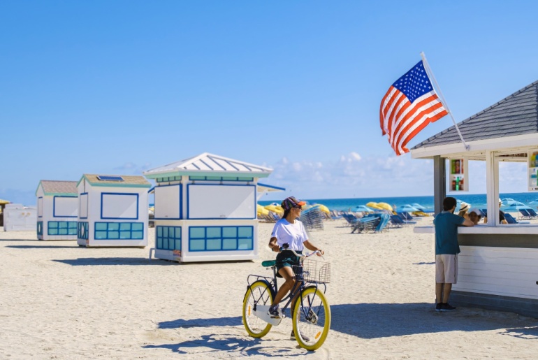 Young women on the beach in Miami with a bicycle
