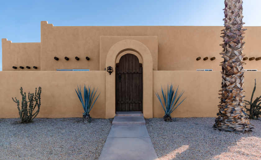 Adobe Southwest pueblo style home in the American desert with cactus and a palm tree