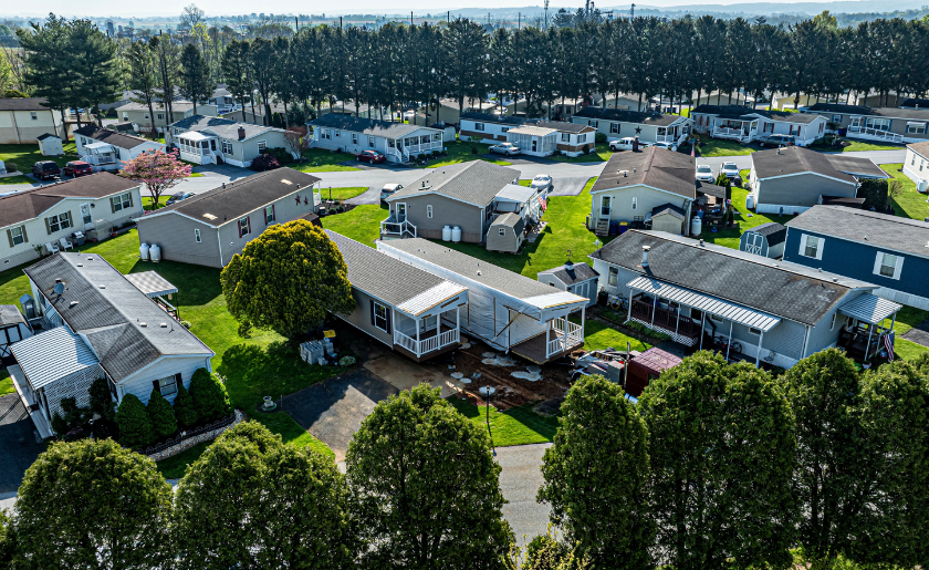 An aerial view of a manufactured mobile prefab double wide home being installed in a lot in a park