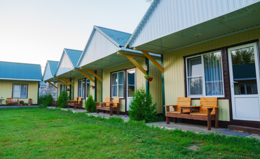 One-story motel houses with individual entrance, small terrace, shared green space.