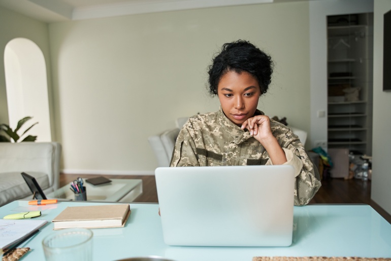 Military woman working behind laptop.
