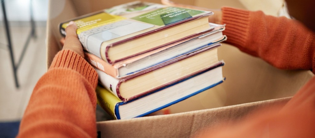 Women placing used books in cardboard box
