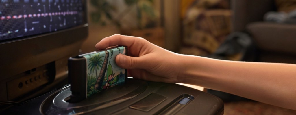 Close up of hand inserting game cartridge into retro gaming console.