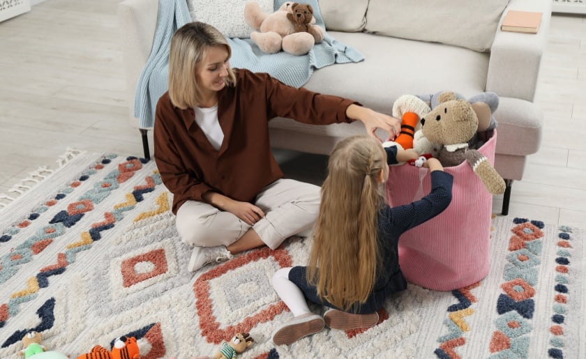 Woman and daughter putting toys away together.