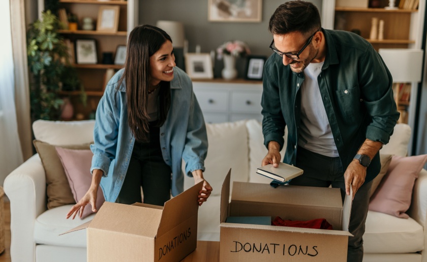Young couple packing books in boxes for donations.