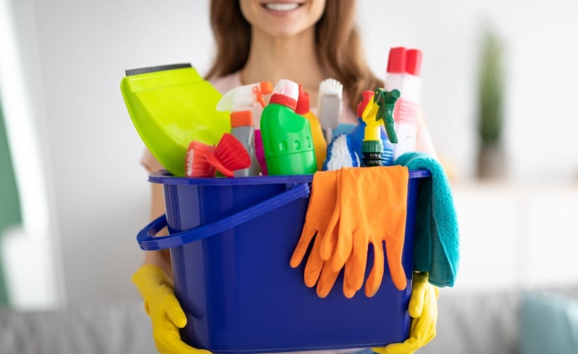 Woman holding cleaning supplies.