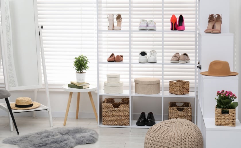 Shoe storage with shelving unit with different footwear, accessories and mirror indoors.