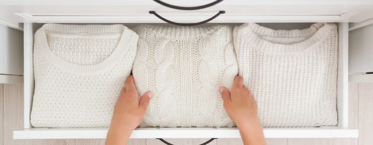 Folded sweaters in drawer.