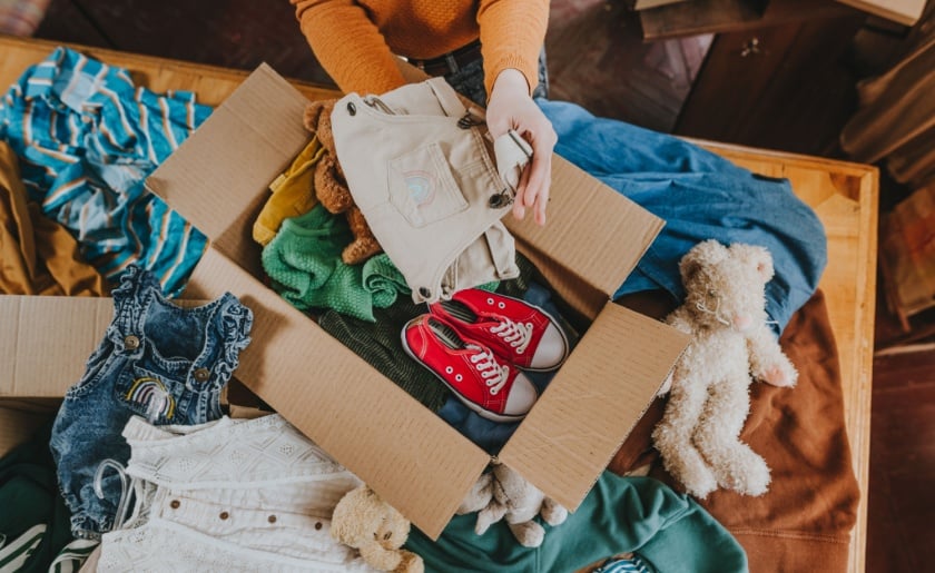 Close-up of woman sorting an old out-of-use kid toy and clothes.