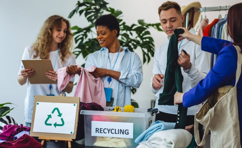 Group of young women and man, sorting clothes for donation and recycling.