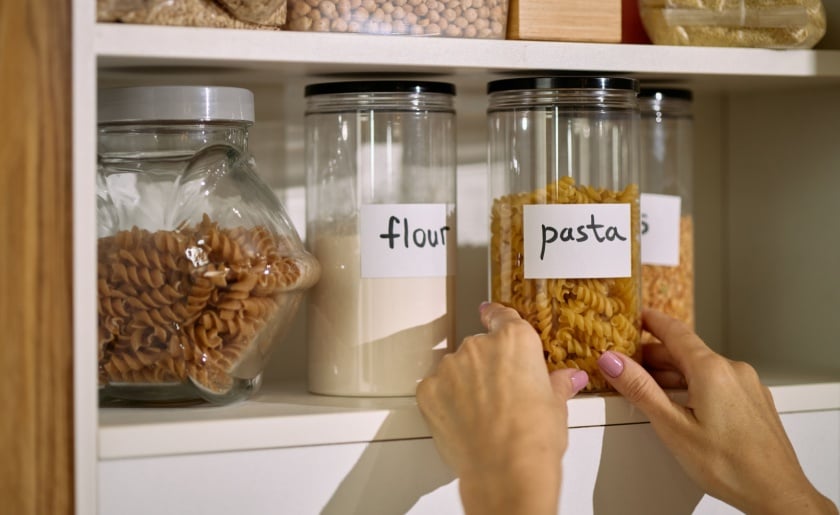 Labeled clear containers in kitchen pantry.