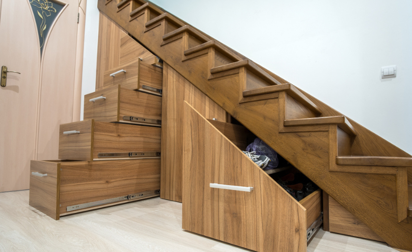 Custom-built pullout cabinets on glides in slots under stairs
