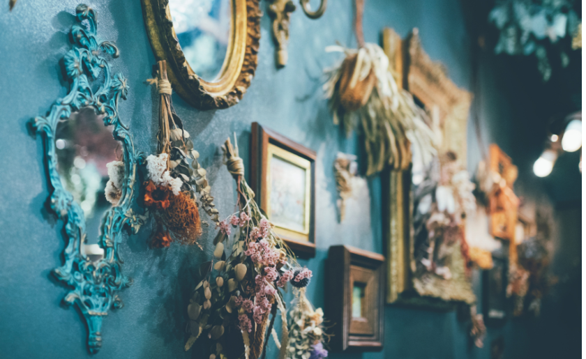 Maximalist living room with blue walls decorated with dried flowers, photo frames and mirrors.