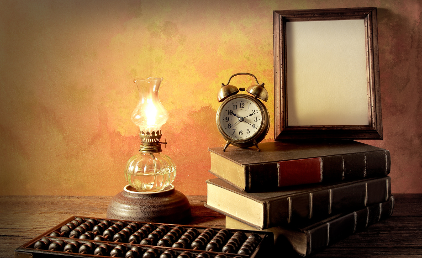 Stack of books with frame and clock on top.