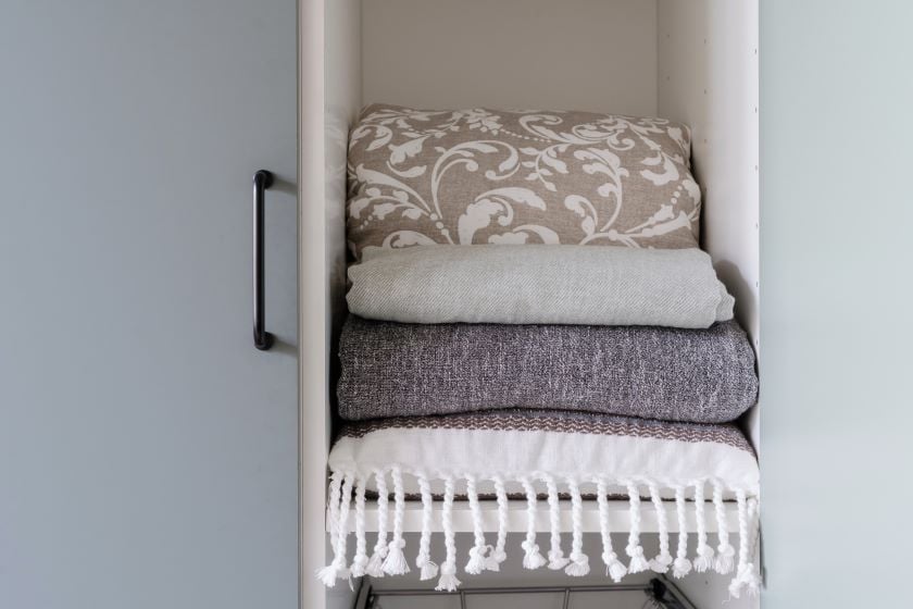 stack of blankets in linen closet
