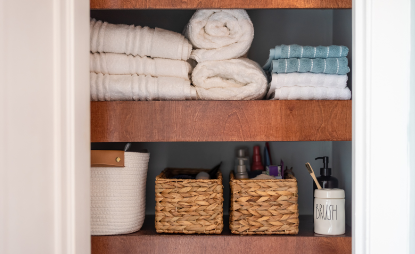 Organized bathroom cabinet, with labeled toothbrush jar, towels, basket for skincare products, etc