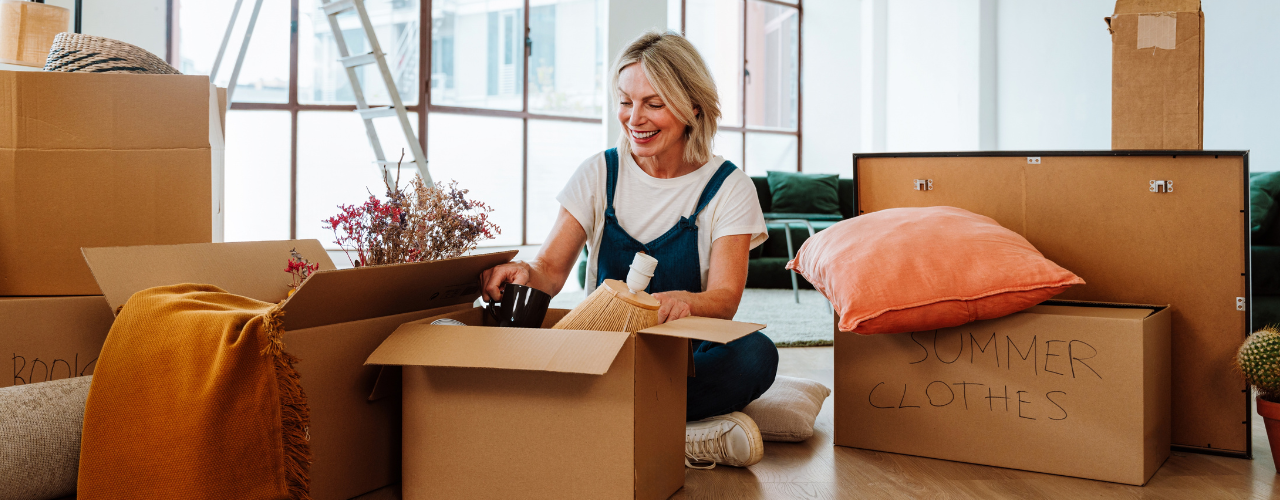 Middle aged woman surrounded by moving boxes.