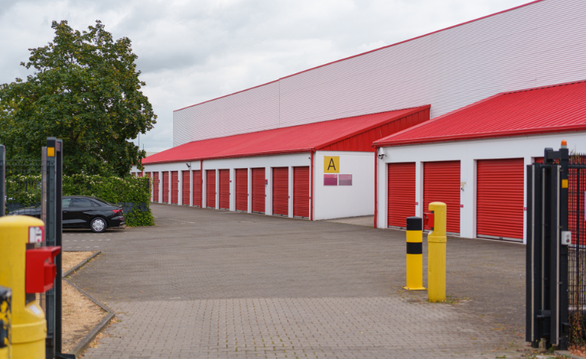 Row of self storage units with red doors inside a secure commercial facility.