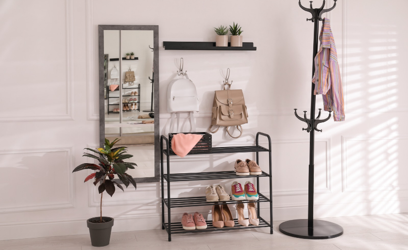 Black shelving unit for storing shoes and different accessories near white wall in hall