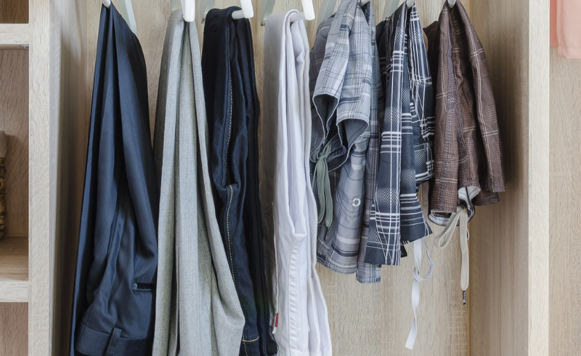 Clothes hanging from longest to shortest in wooden wardrobe at home