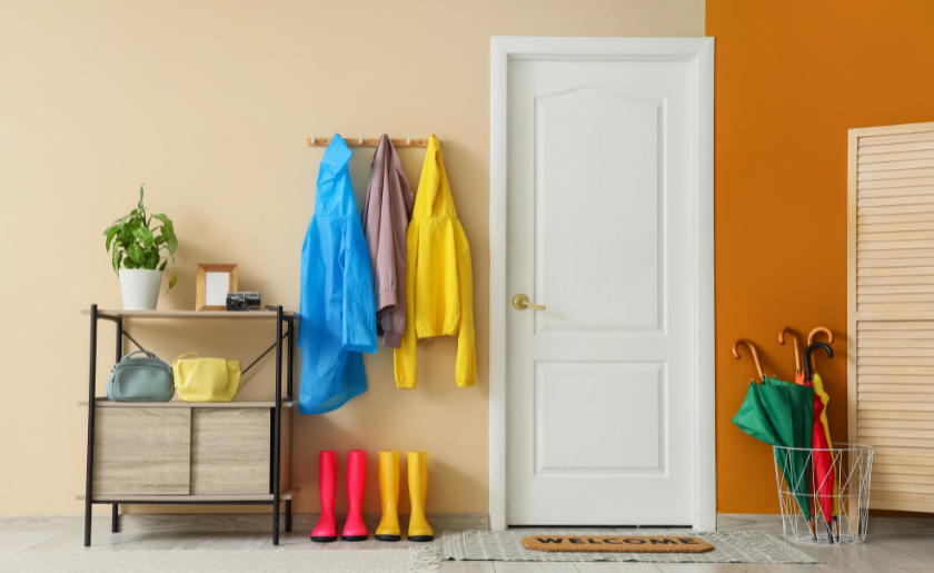 Modern home entryway with colorful rain gear, storage shelf, and welcome mat for interior design