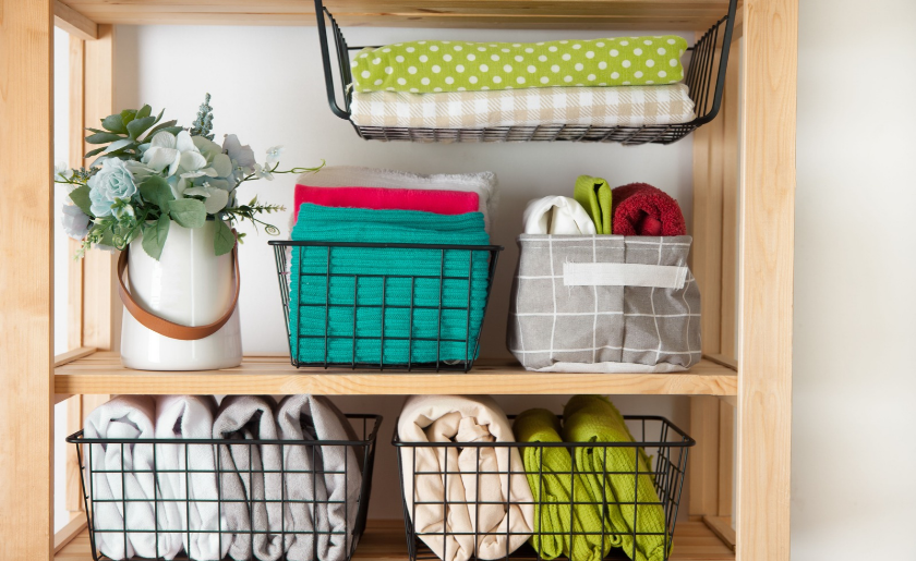 Neatly folded bed sheets in the metal black baskets and fabric baskets for wardrobe.