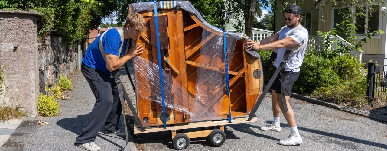 Piano movers moving a grand piano with proper equipment