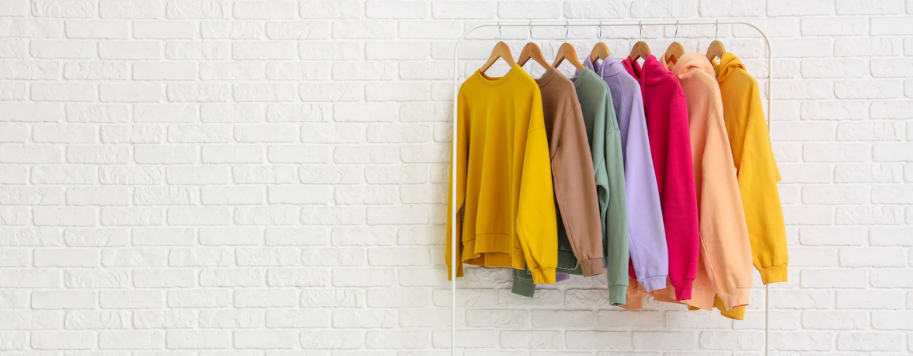 Rack with sweatshirts brick wall.
